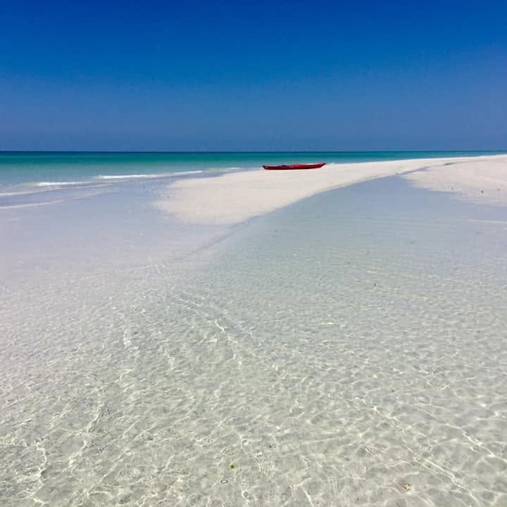 Clear shallow water over a white sandbar with a red kayak at Fort De Soto Park