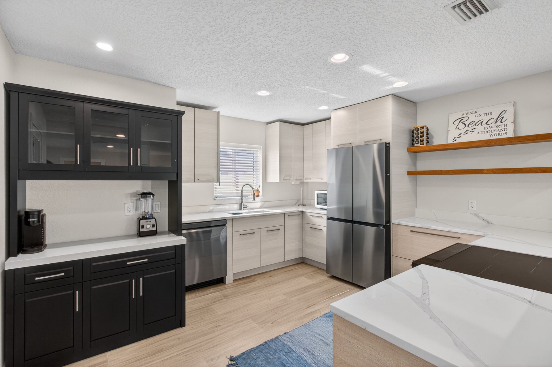 Renovated kitchen with quartz counters, induction range, and stainless refrigerator