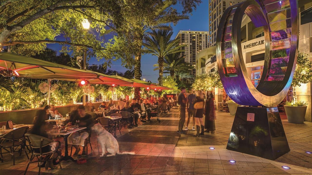 Outdoor cafe tables lit with string lights along a downtown St. Petersburg street at night